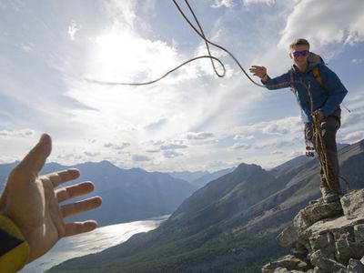 Man throwing a rope to a person holding out a hand to catch it