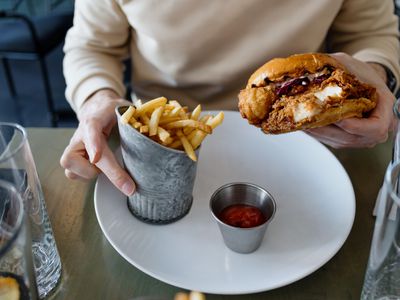 A person eating a fried chicken sandwich and fries