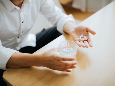 Close up of man holding a glass of water and medication in his hand