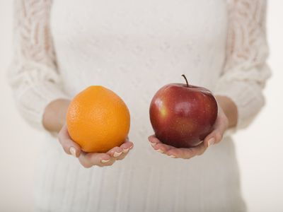 Close up of woman holding apple and orange