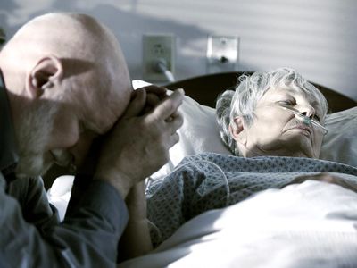 Elderly man with his wife as his wife begins the dying process