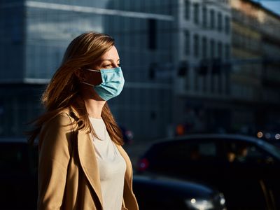 A person wears a mask as they walk down the street to protect against spreading COVID-19