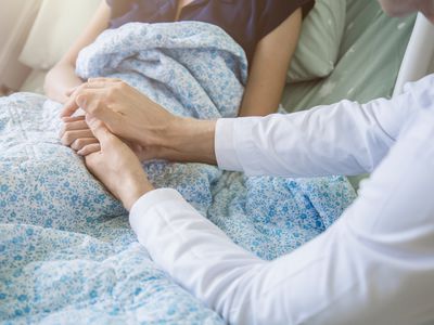 Doctor holding patient's hand, helping hand concept and comforting her