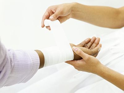 Nurse wrapping bandage around patient's wrist,close-up on hands