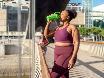 A person drinks a protein shake from a sports bottle after exercise