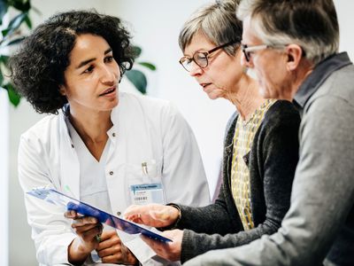 Female doctor showing test results to middle-aged couple in a hospital. 