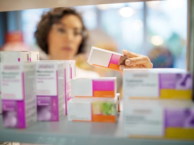 female physician looking at medications on shelf