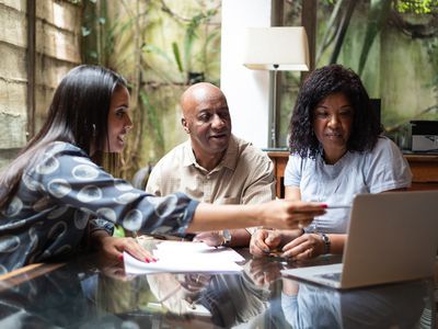 Three people looking at laptop in office