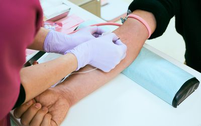 Female nurse is taking blood of a senior patient at hospital