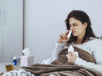 Woman using nasal spray in bed