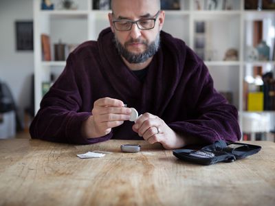 A man sitting at a table testing his blood sugar.