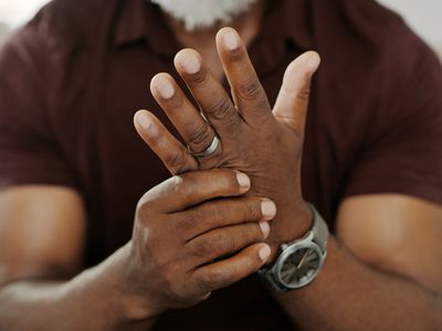 Cropped shot of an unrecognizable man sitting alone on his sofa at home and suffering from arthritis in his hand