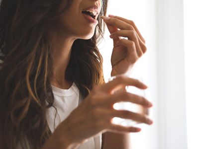 Young female taking supplements at home