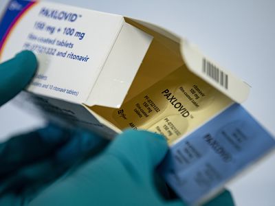 A person with gloved hands holds the medication Paxlovid