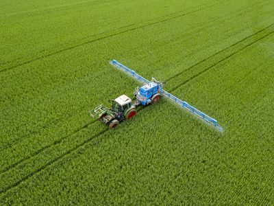 Aerial view of tractor spraying wheat field