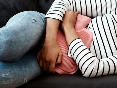 close-up of woman using hot water bottle on her abdomen