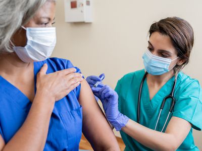 Nurse gives older adult healthcare worker the Covid-19 vaccine