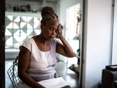 Mature woman with hand to head at home - stock photo