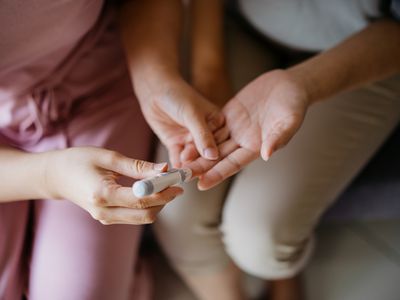 Close-up of provider helping person check blood sugar level