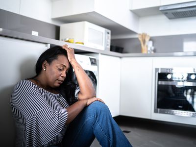 Depressed woman sitting on the floor in a kitchen