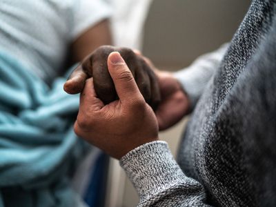 Close up shot of son holding father's hand at the hospital