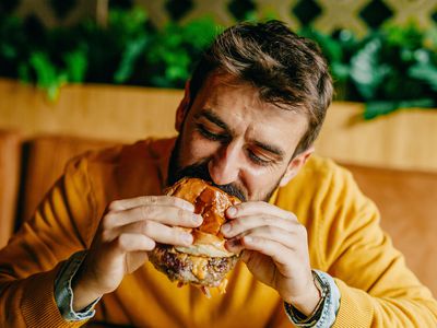 man eating a greasy burger