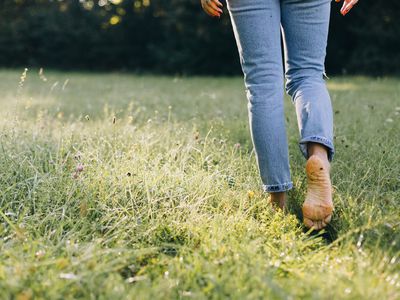 Image of a woman walking barefoot in a field. 