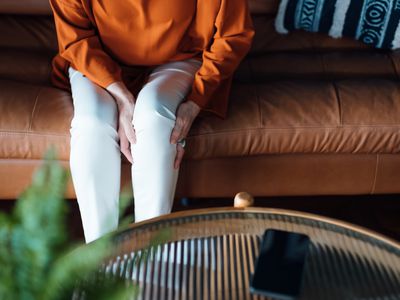 Person on couch experiencing knee pain from arthritis