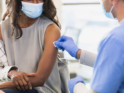 A healthcare provider prepares the injection site with an alcohol swab so that he can inject the vaccine.