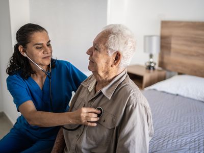 Nurse checking senior's heartbeat at home