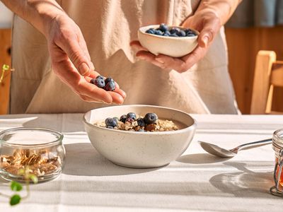 close-up of woman adding berries to her breakfast