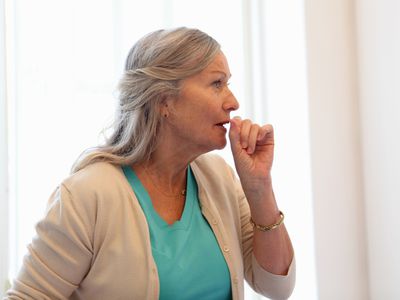 Older woman coughing into her hand