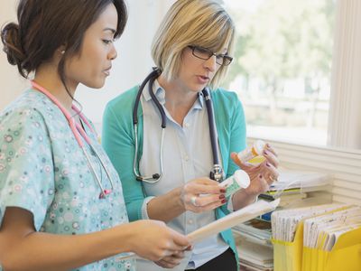 Female doctor and nurse with pill bottles and files in clinic