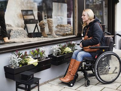 Disabled woman in wheelchair looking in store window