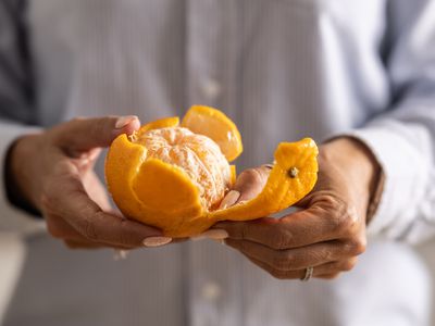 person peeling orange