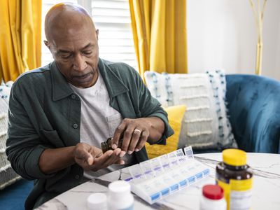 Older male sorting prescription medications at kitchen table