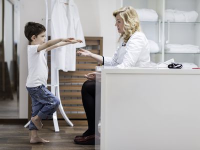 Physical therapist doing a neurological exam with a young boy.