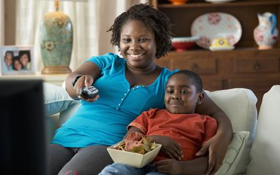 Black mother and son watching television together