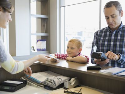 Receptionist helping father and son in dentists office