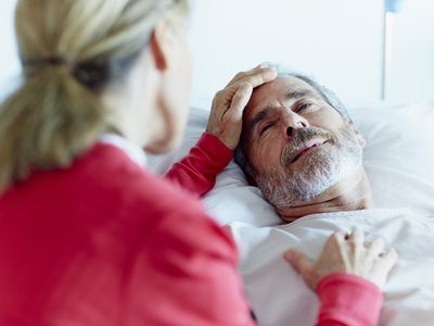 an older woman touching an older man's forehead