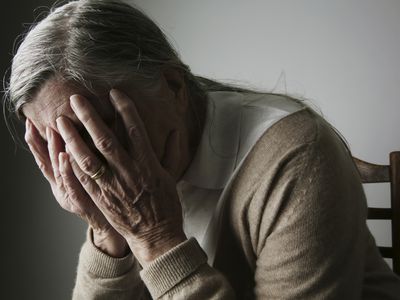 elderly woman with hands covering face