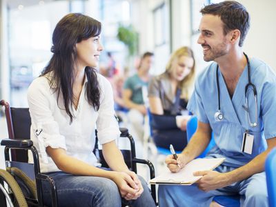 Patient in wheelchair talking to nurse in hospital