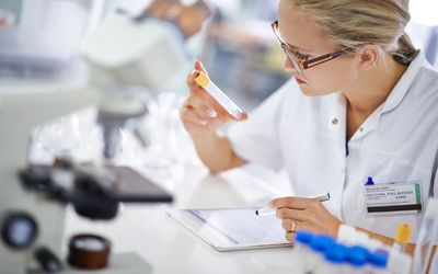 Lab tech looking at sample and recording findings