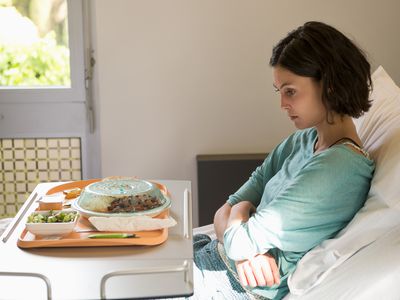 Anorexia nervosa patient with a food tray in hospital ward