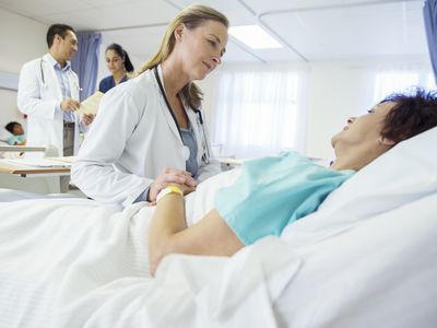 Woman hospitalized in observation status being checked on by her doctor.