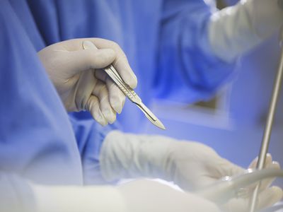 Mature surgeon using scalpel during surgery