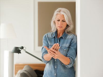 Senior woman standing touching hand