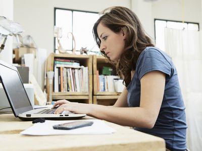 Young woman sitting at desk, using laptop