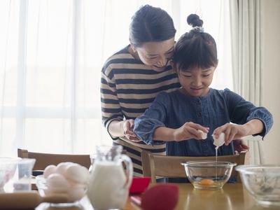 A woman and her daughter preparing an egg