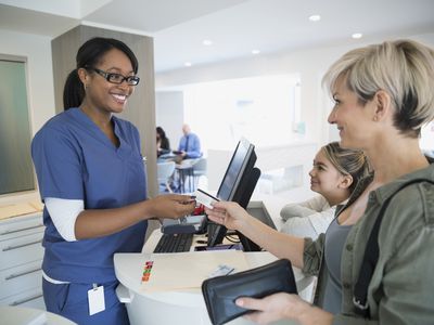 Patient paying nurse with credit card in clinic